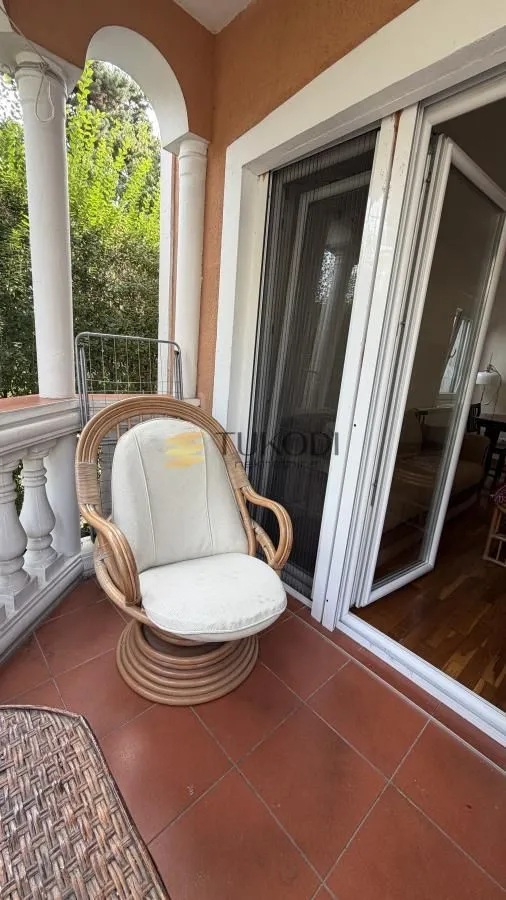 Covered terrace with a wicker armchair and exterior view.