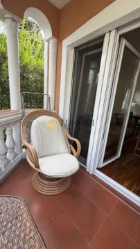 Covered terrace with a wicker armchair and exterior view. - image 18
