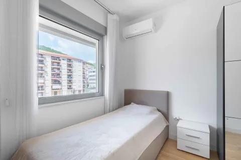 Small bedroom with a bed, white nightstand, and air conditioning unit. - image 24