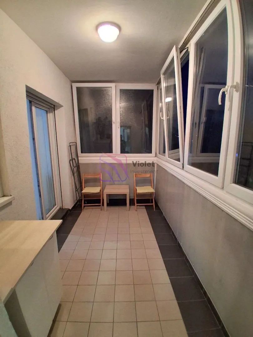Zastakljeni balkon sa keramičkim pločicama i prozorima duž cijelog zida.
