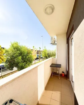 Covered balcony with a view of the street and greenery. - image 2