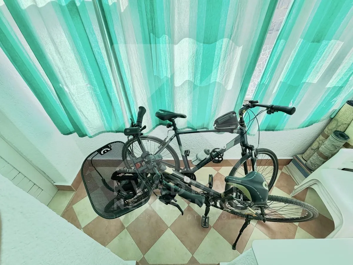 Covered terrace with bicycles and bright green curtains.