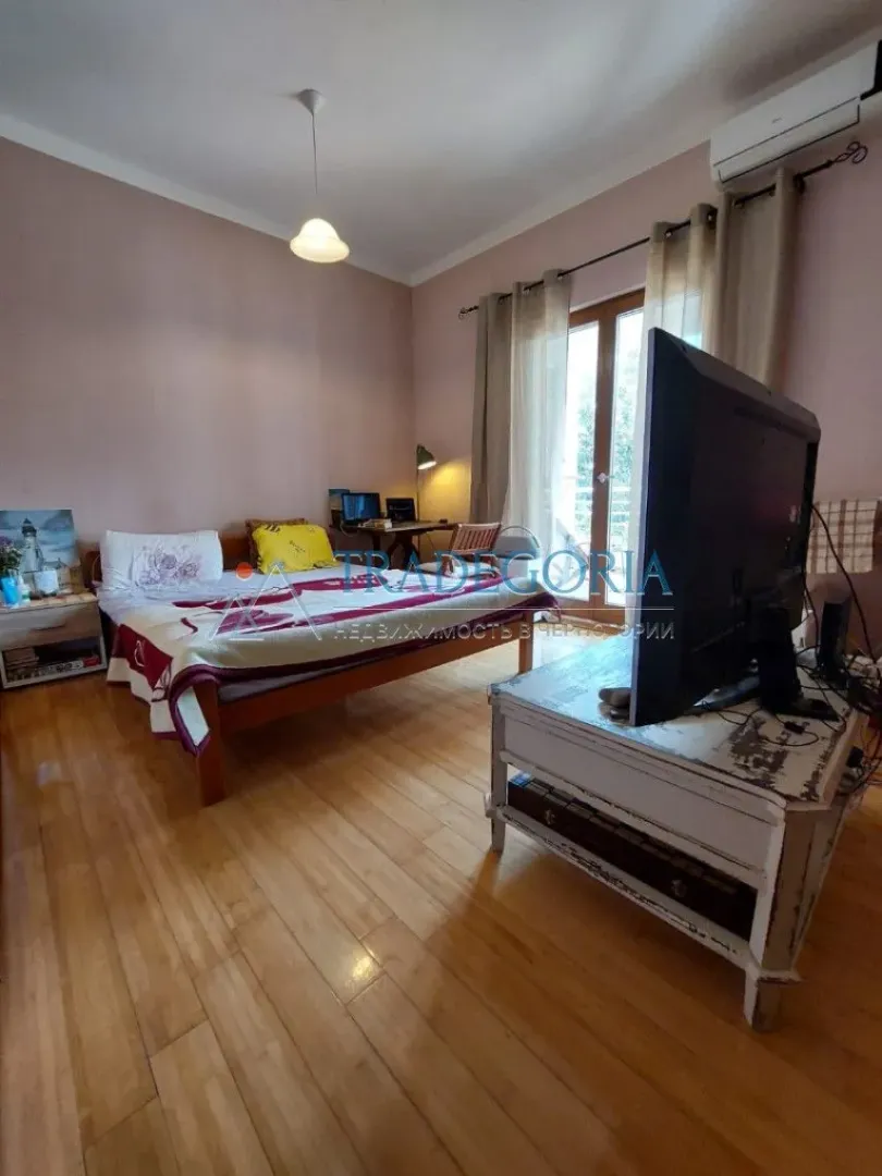Namještena spavaća soba sa bračnim krevetom, TV-om i izlazom na terasu.