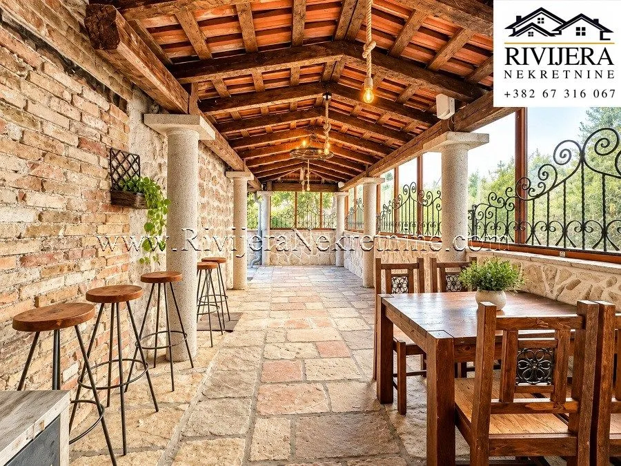 Covered terrace with wooden beam structure, stone pillars, and a dining table.
