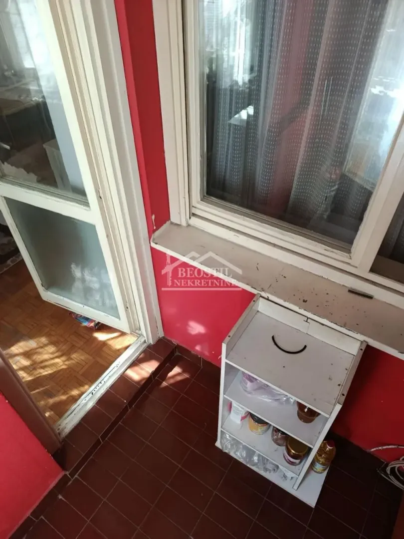 Small enclosed balcony with a shelf and a window view.