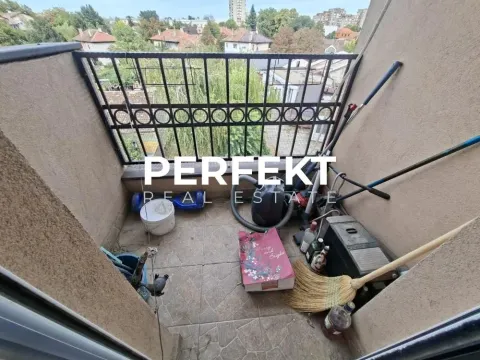 Manji popločani balkon sa metalnom ogradom i odloženim kućnim potrepštinama. - image 15