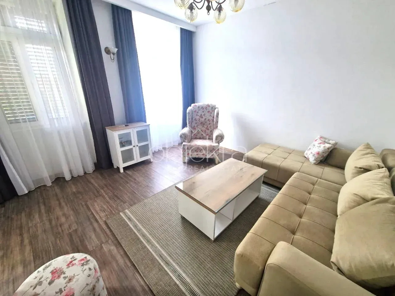 Dnevna soba sa garniturom, stočićem i foteljom pored prozora.