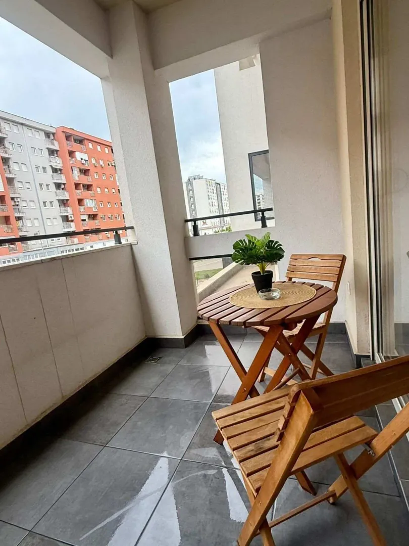 Balcony with a wooden table and two chairs.