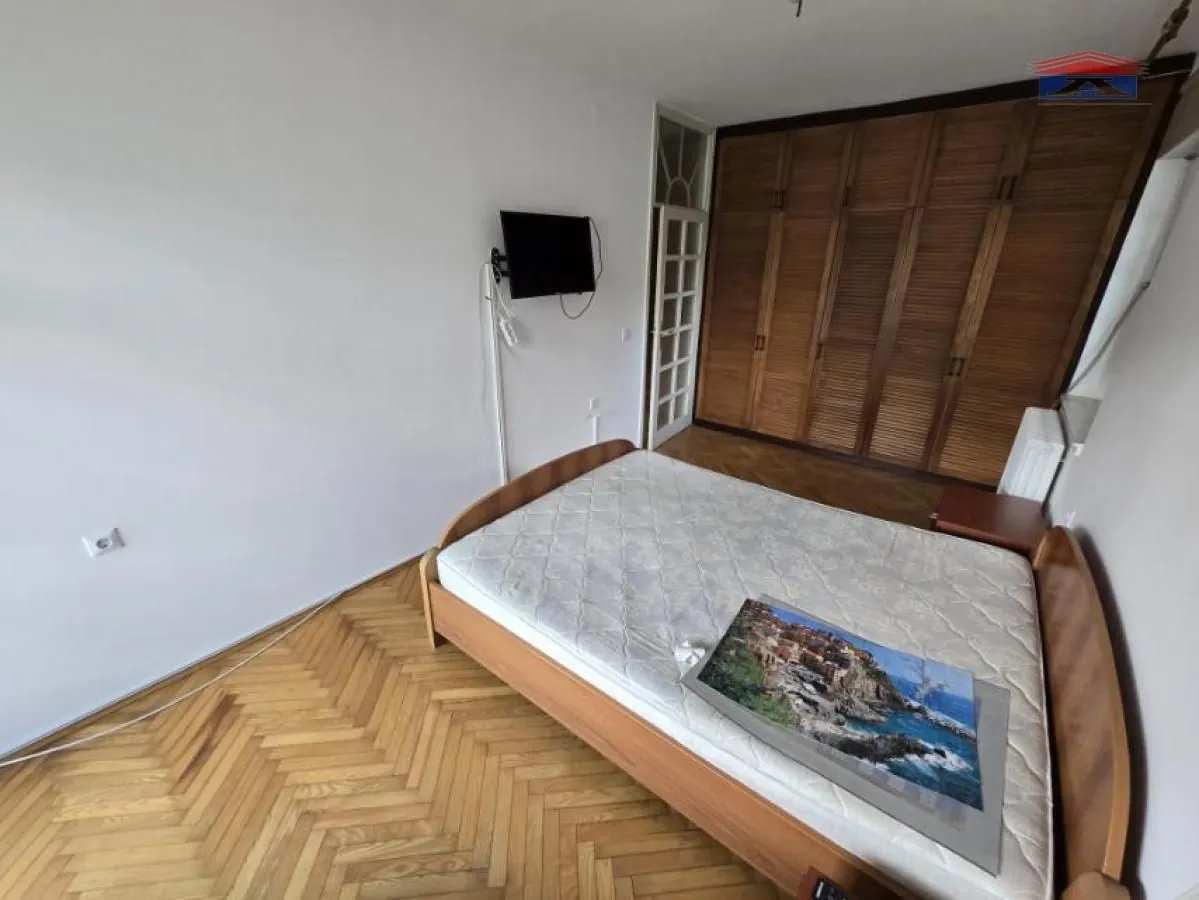 Bedroom with a double bed, wooden wardrobe, and parquet flooring.
