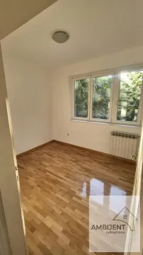 Prazna soba sa parketom i prozorom koji gleda na zelenilo. - image 3