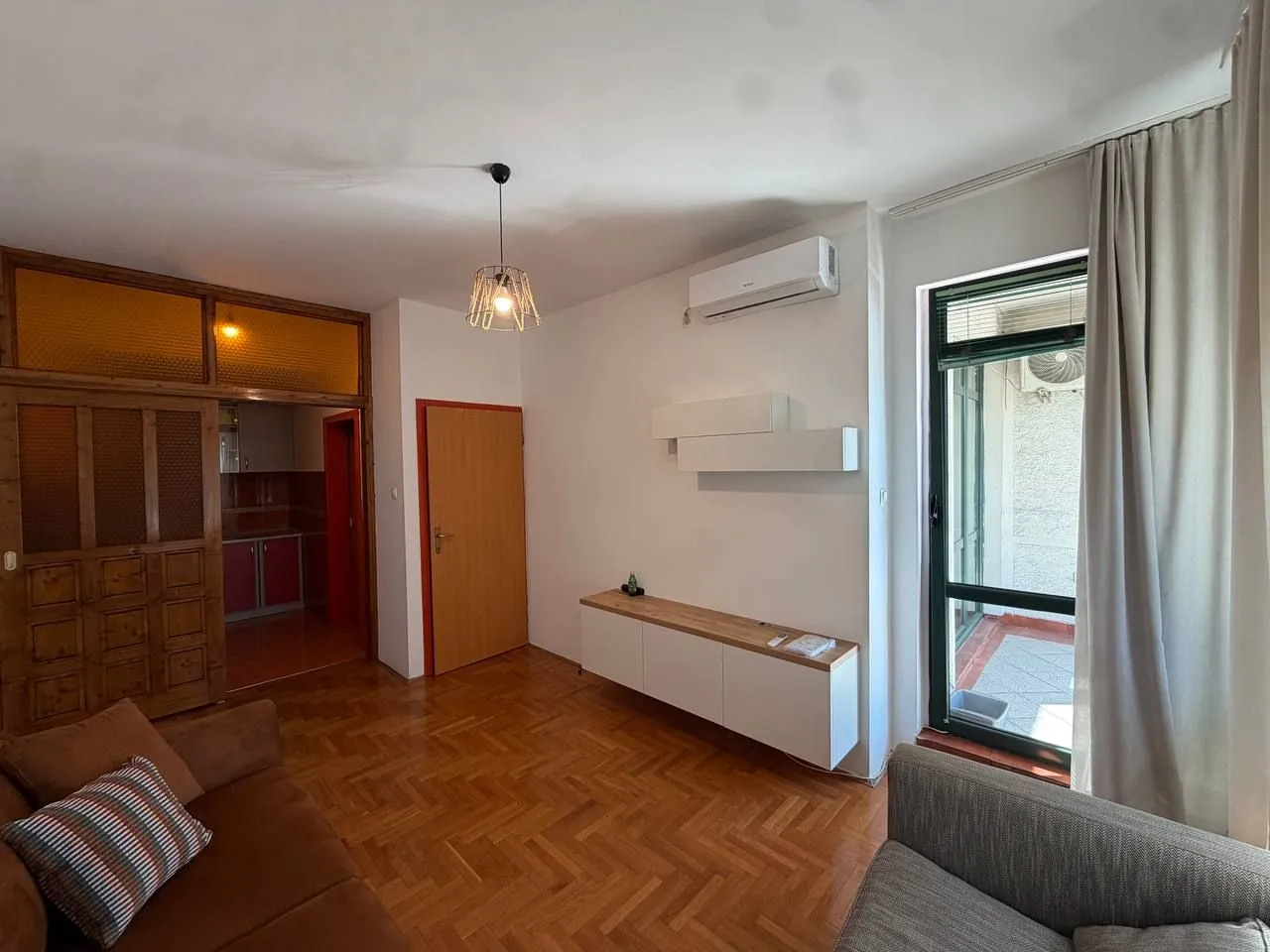 Living room with parquet flooring, furniture, and access to the terrace.