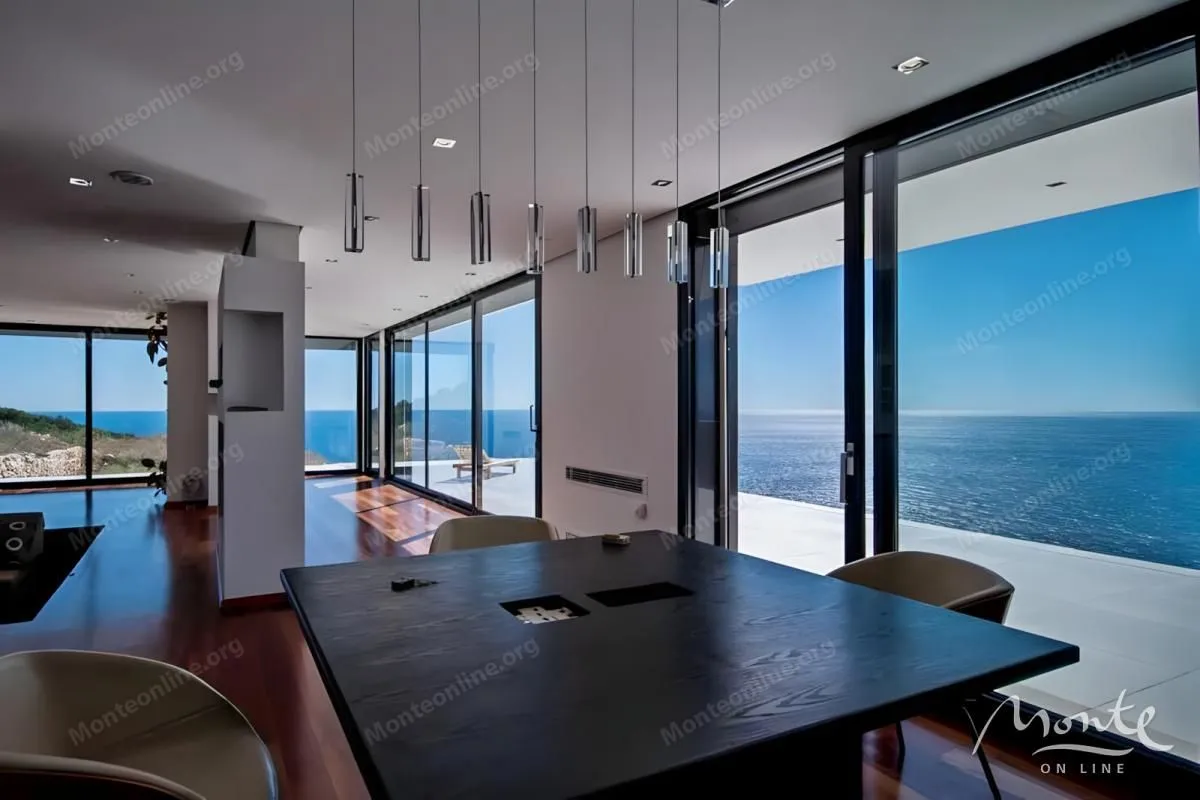 Spacious living room with dining area and sea view through large glass surfaces.