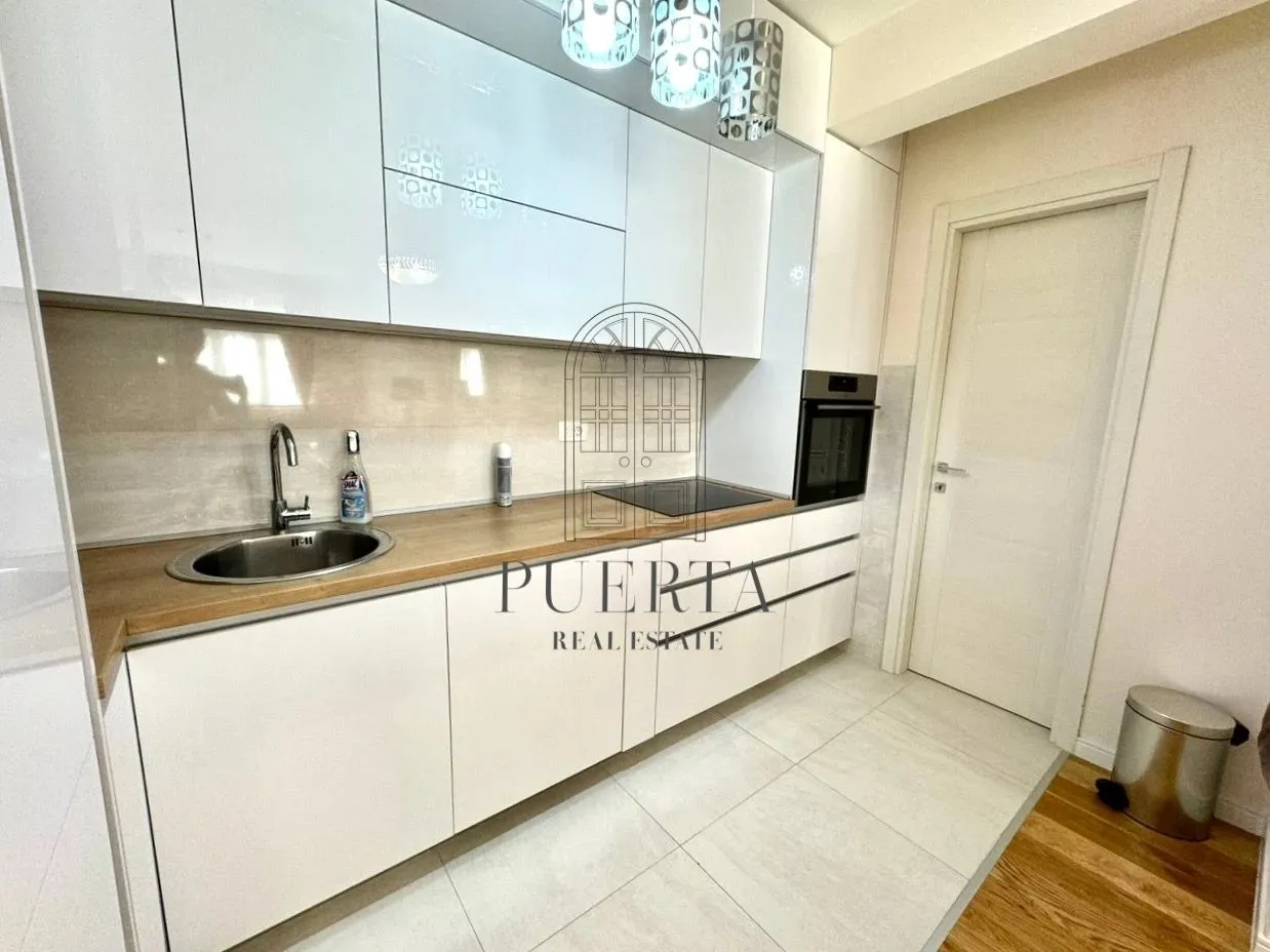 Modern white kitchen with a wooden countertop and built-in appliances.
