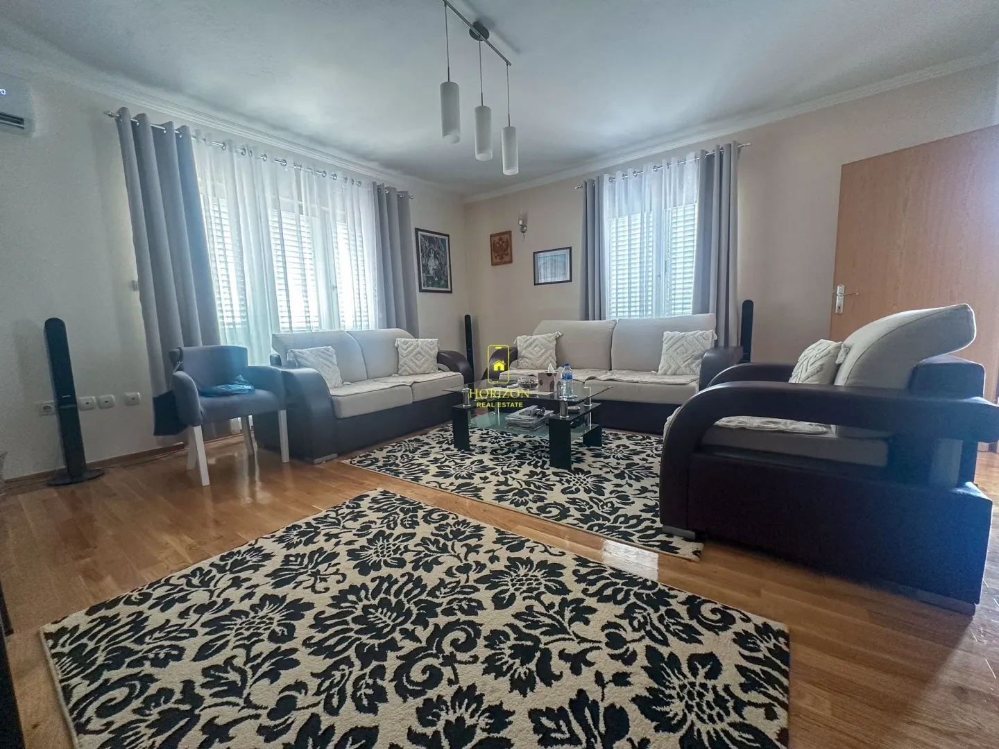 Prostrana dnevna soba sa garniturom za sjedenje i tepisima.