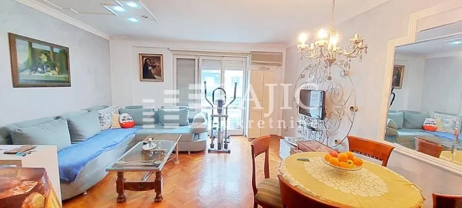 Spacious living room with a sofa set, dining table, and large mirror.