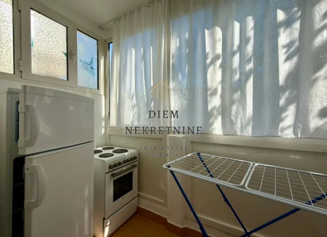 Small kitchen with a refrigerator, stove, and laundry drying rack.