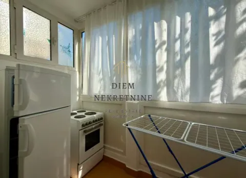 Small kitchen with a refrigerator, stove, and laundry drying rack. - image 8