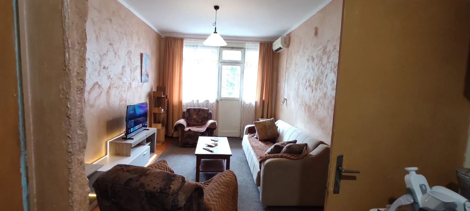 Living room with sofa set, coffee table, and television.