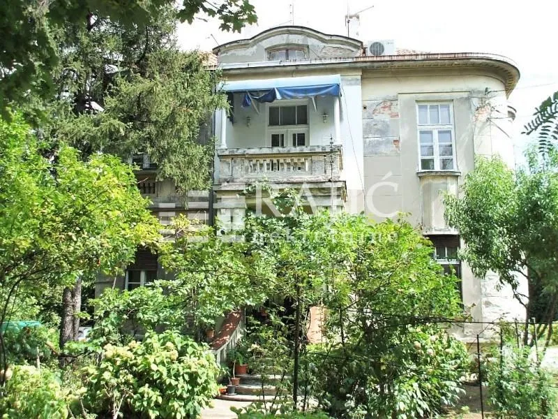 Spoljašnji izgled starije kuće sa dvorištem i zelenilom.