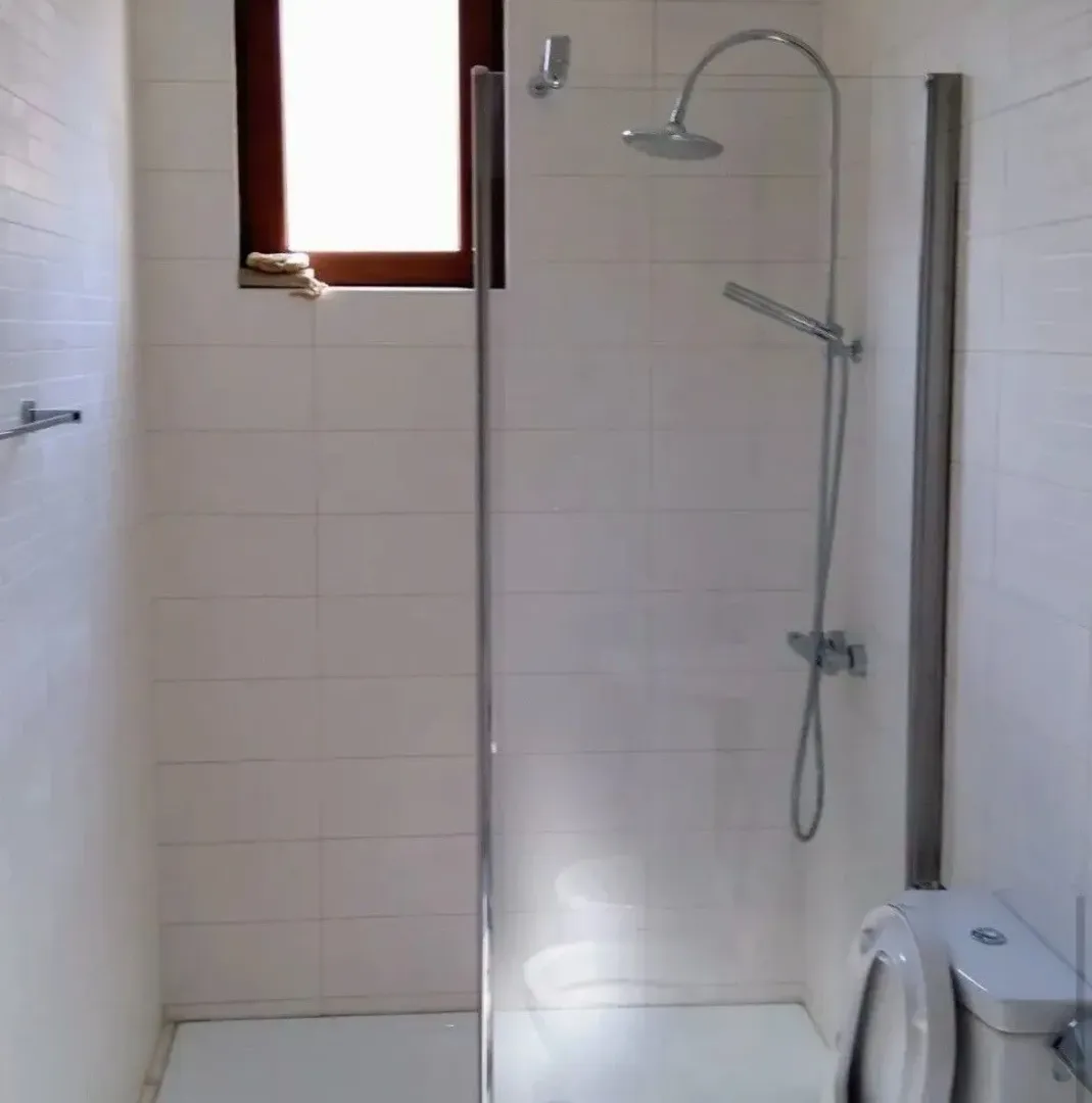 Bathroom with a glass shower enclosure and white tiles.