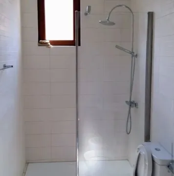 Bathroom with a glass shower enclosure and white tiles. - image 11