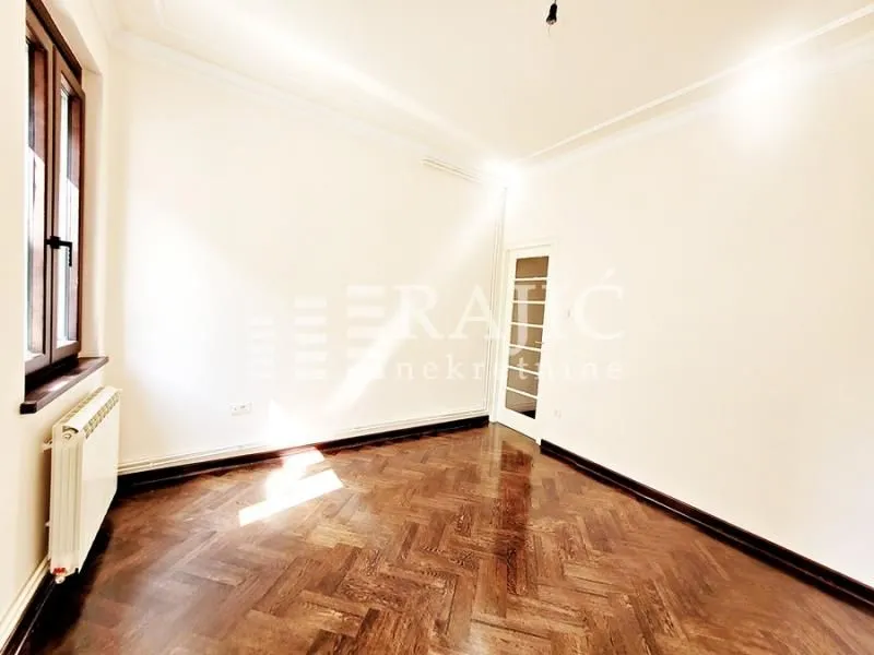 Empty room with parquet flooring and white walls.