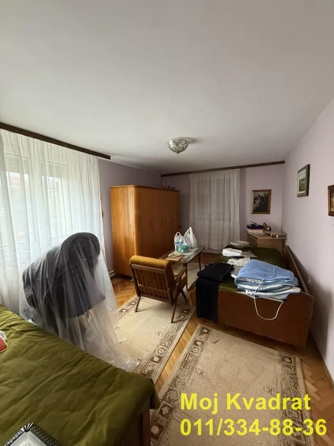 Nameštena spavaća soba sa krevetom, ormanom i foteljom.