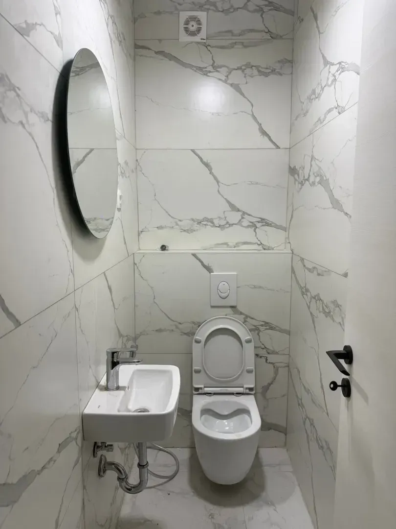 Modernly equipped bathroom with white marble-pattern ceramic tiles.