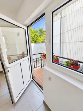 Pogled iz enterijera kroz otvorena vrata na manji balkon sa cvećem i drvenim podom. - image 5