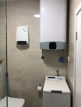 Small bathroom with a water heater, washing machine, and sanitary fixtures. - image 3