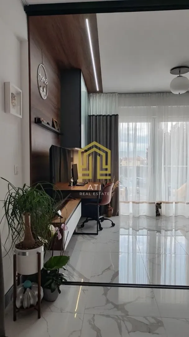 Dnevni boravak sa radnim kutkom i svijetlim pločicama na podu.
