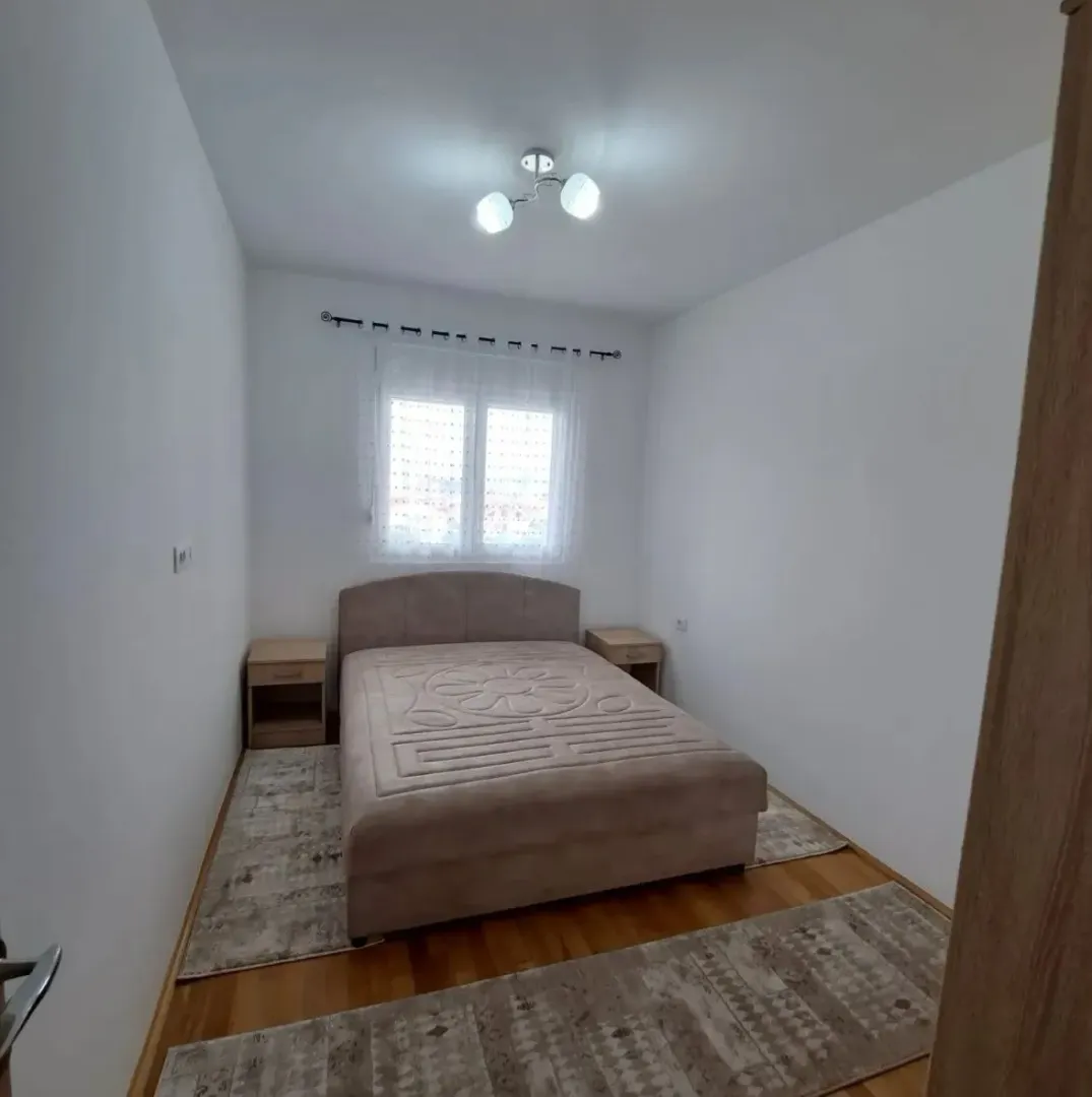 Namještena spavaća soba sa bračnim krevetom, noćnim stočićima i prozorom.