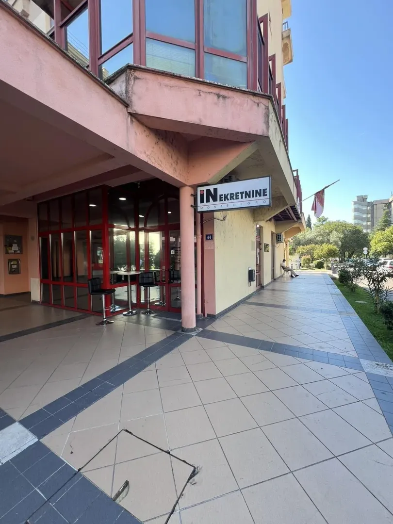 Exterior view of a ground-floor commercial space with a tiled walkway.