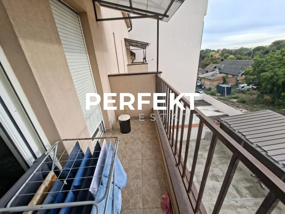 Dugi balkon sa metalnom ogradom i pogledom na okolinu.