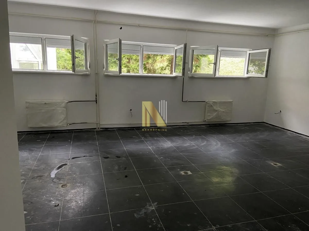 Empty room with dark floor tiles and open windows.