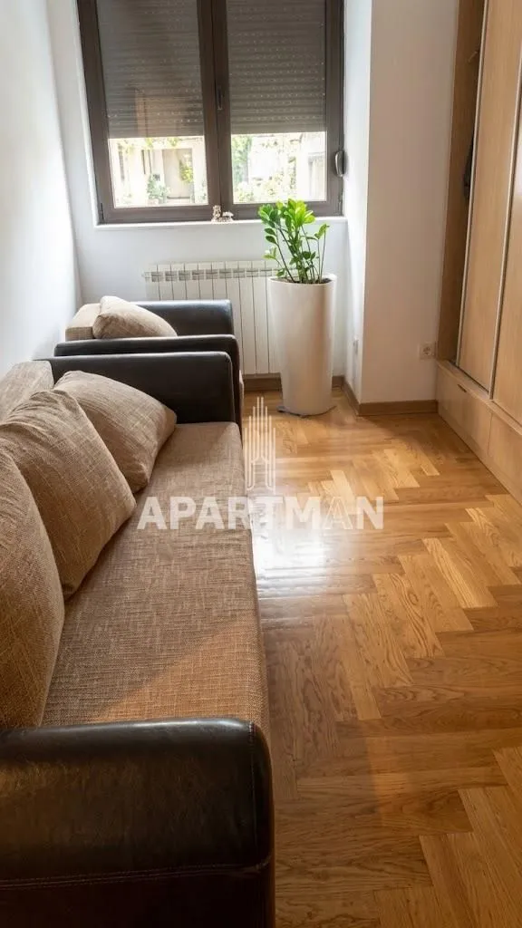 Small living room with a sofa, hardwood flooring, and a wardrobe along the wall.