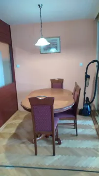 Dining room with a wooden table and chairs, and a vacuum cleaner visible in the corner. - image 3