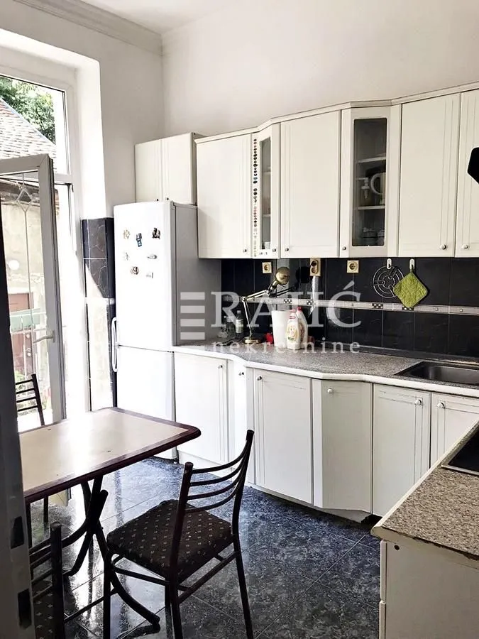White kitchen with dining table and access to the terrace.