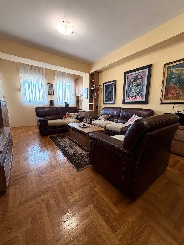 Spacious living room with sofa set and parquet flooring.