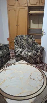 Dnevna soba sa foteljama, tepihom i drvenim ormarom. - image 10