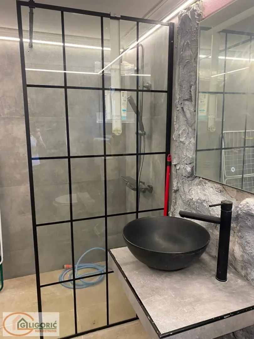Modern bathroom with a vessel sink and a black-framed walk-in shower.