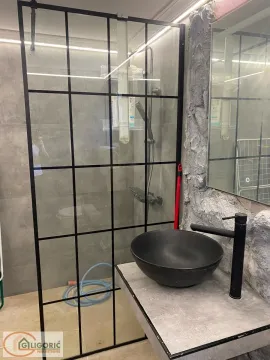 Modern bathroom with a vessel sink and a black-framed walk-in shower. - image 4