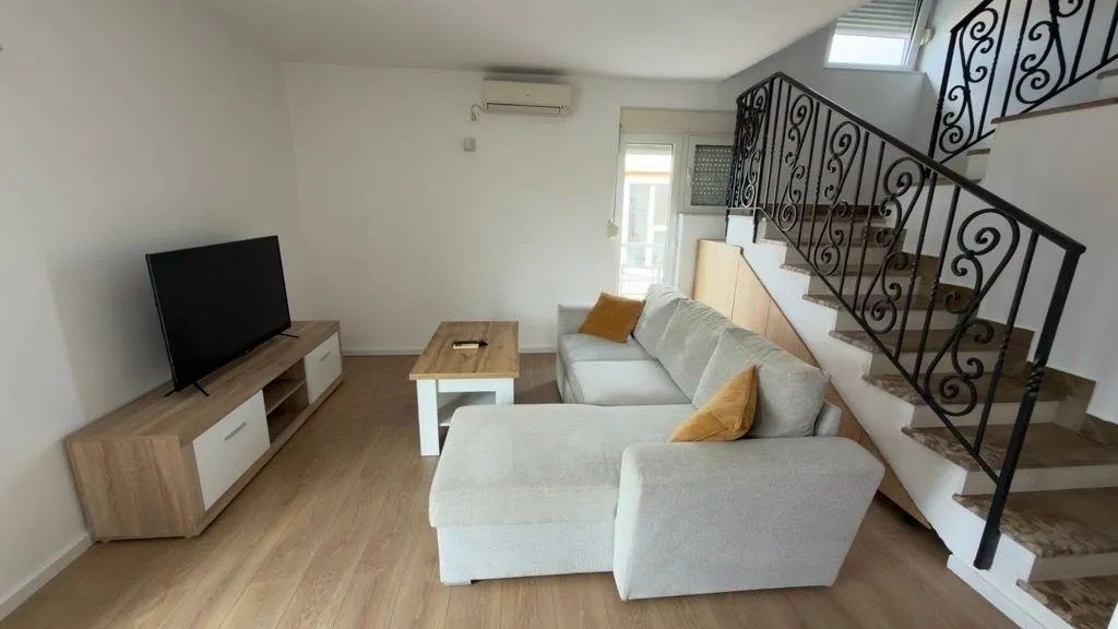 Living room with a sofa, TV stand, and stairs.