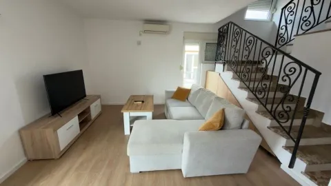 Living room with a sofa, TV stand, and stairs. - image 2