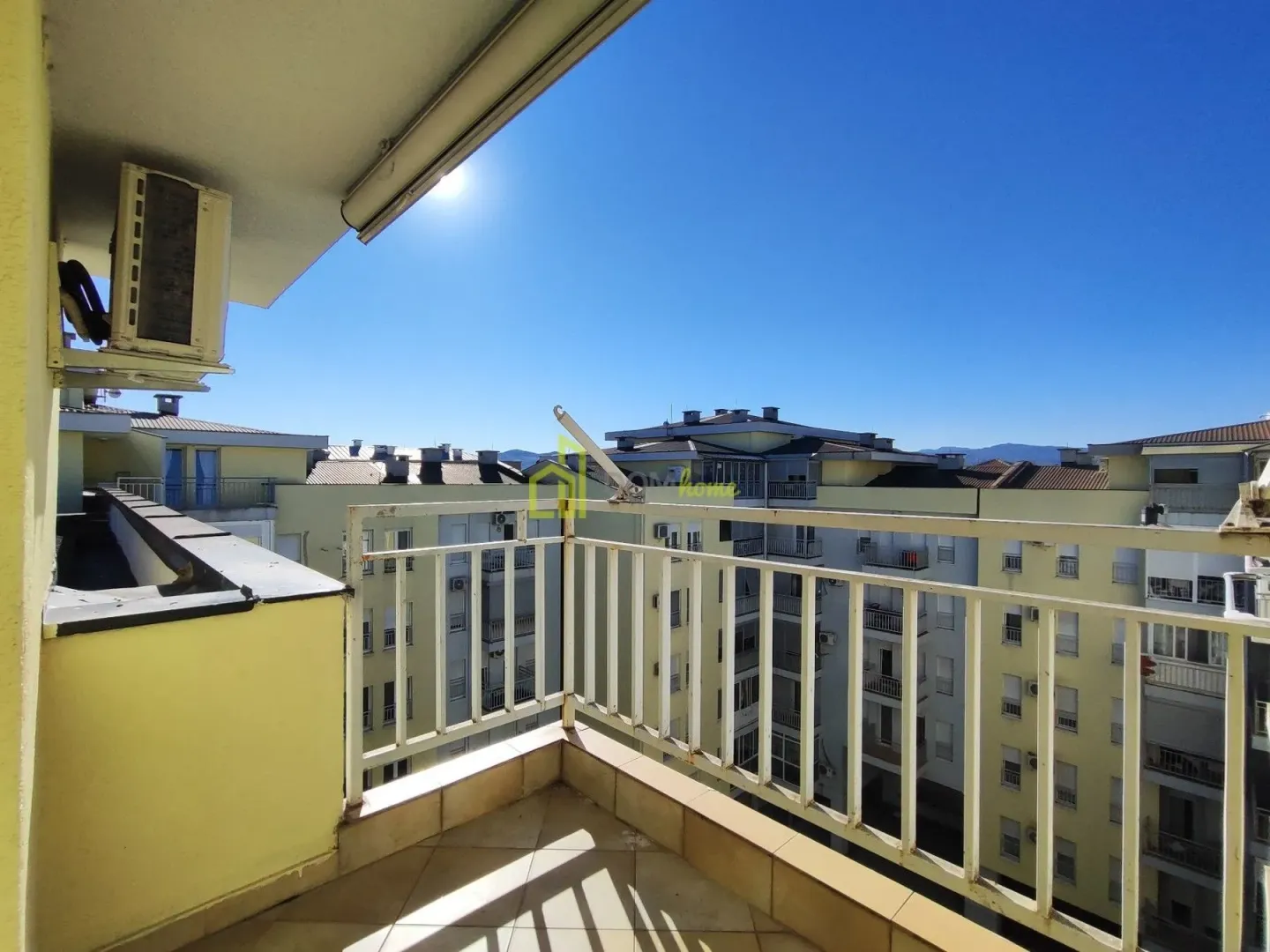 Smaller tiled balcony with a metal railing and a view of surrounding buildings.