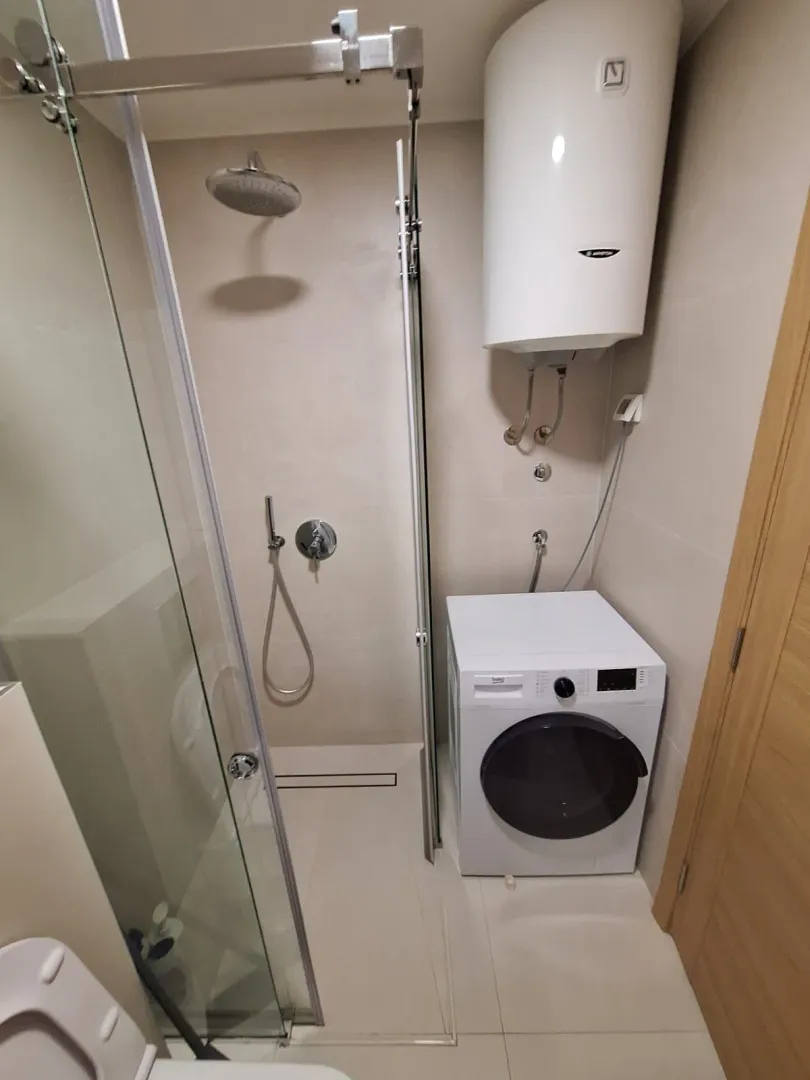 Modern equipped bathroom with a shower cabin and washing machine.