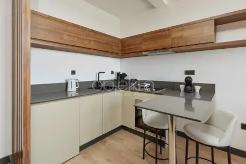 Modern kitchen with wooden upper cabinets, dark countertops, and a small breakfast bar with two bar stools. - image 7