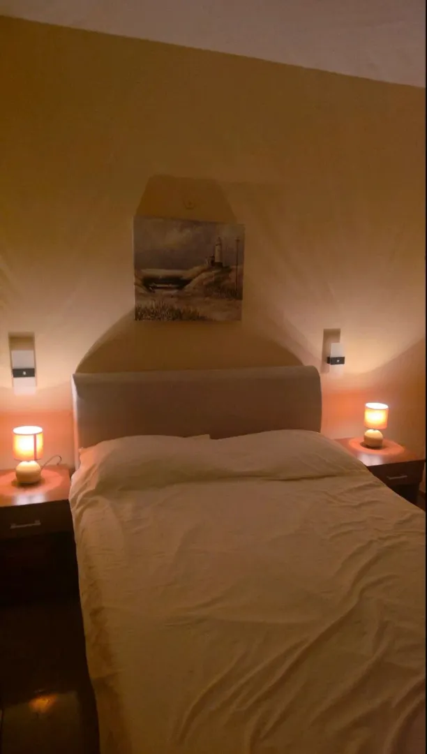 Furnished bedroom with a double bed and nightstands with lamps.