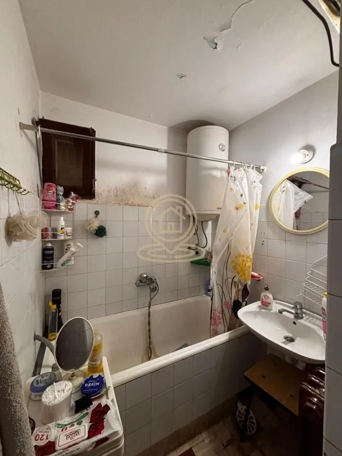 Small bathroom with a bathtub, washbasin, and water heater.