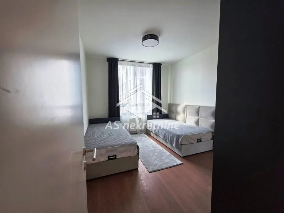 Bedroom with two beds and a window with dark curtains.
